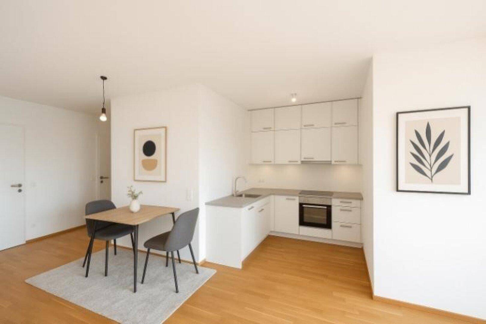 Kompakte, moderne Einbauküche mit Essbereich und Holzboden in offenem Raumkonzept.