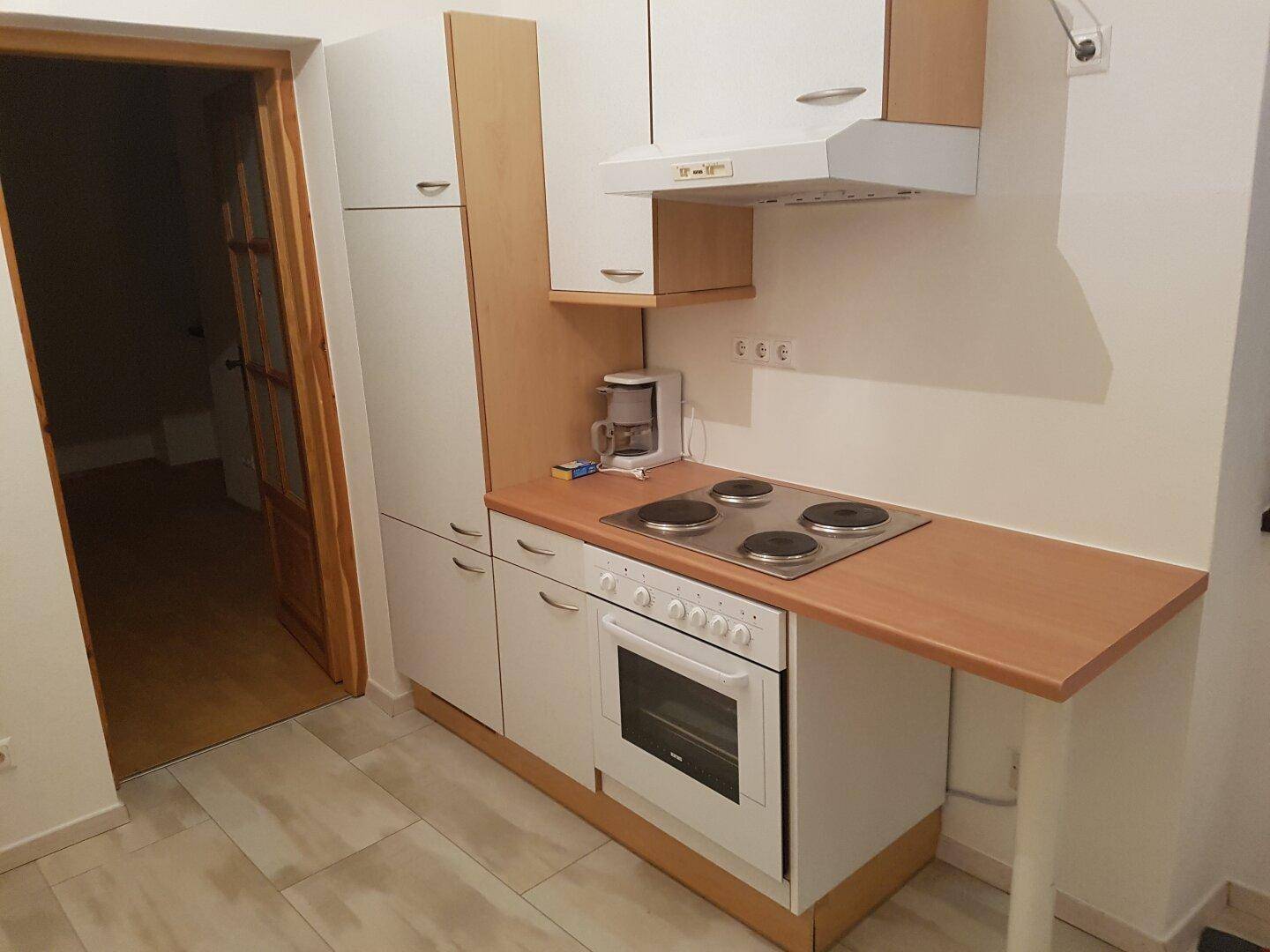 Kleine Einbauküche mit weißen Schränken, Kochfeld und Backofen, ideal für kompaktes Wohnen.