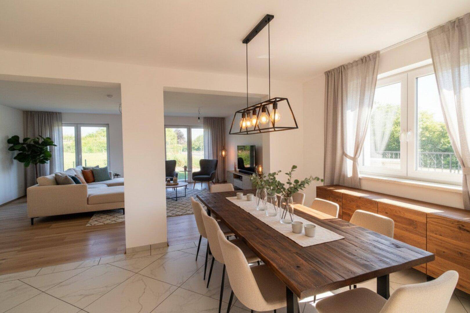 Eleganter Essbereich mit großem Holztisch, modernen Stühlen und Blick in den angrenzenden Wohnbereich.