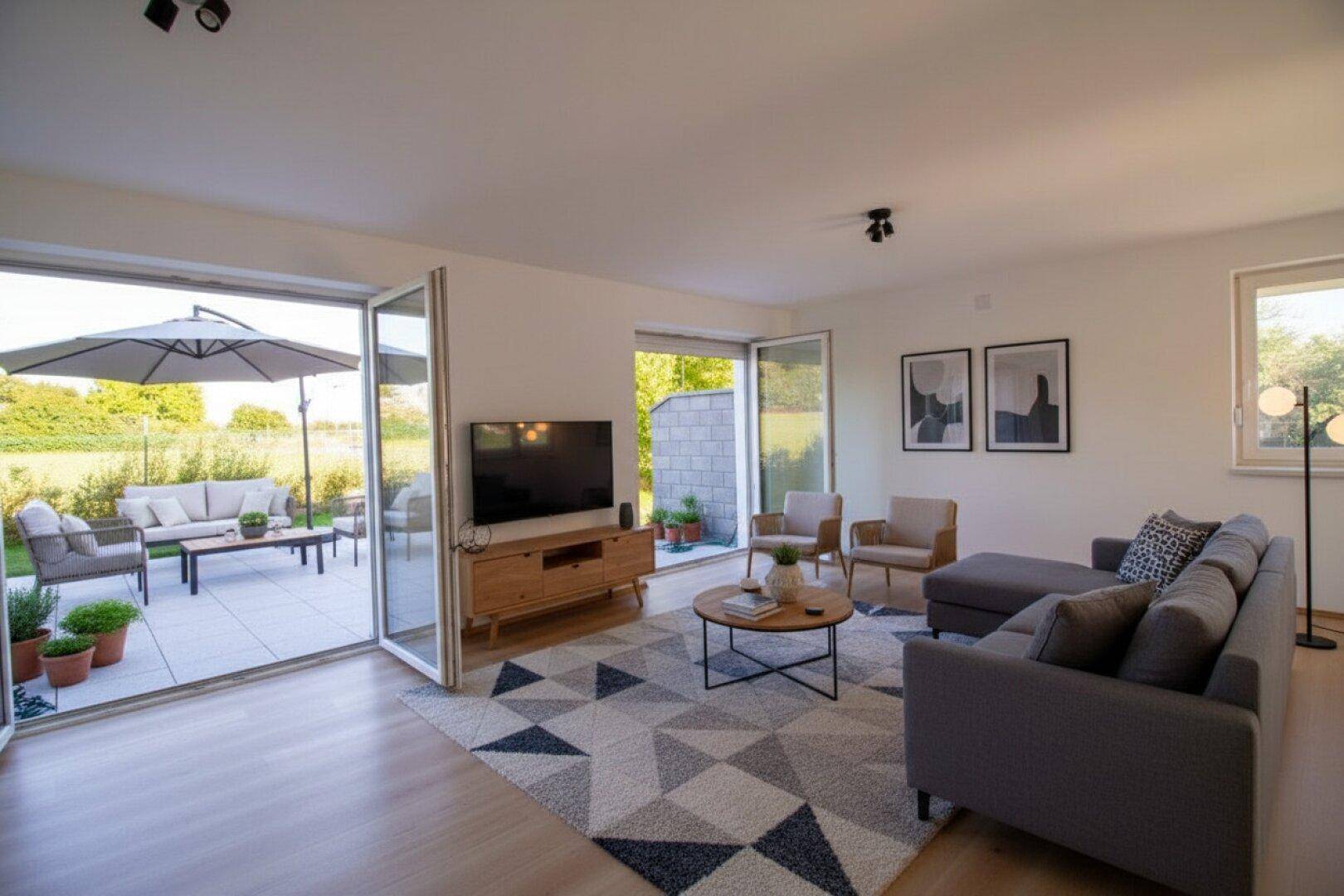 Geräumiges Wohnzimmer mit gemütlicher Sitzecke, Holzboden und direktem Zugang zur sonnigen Terrasse.