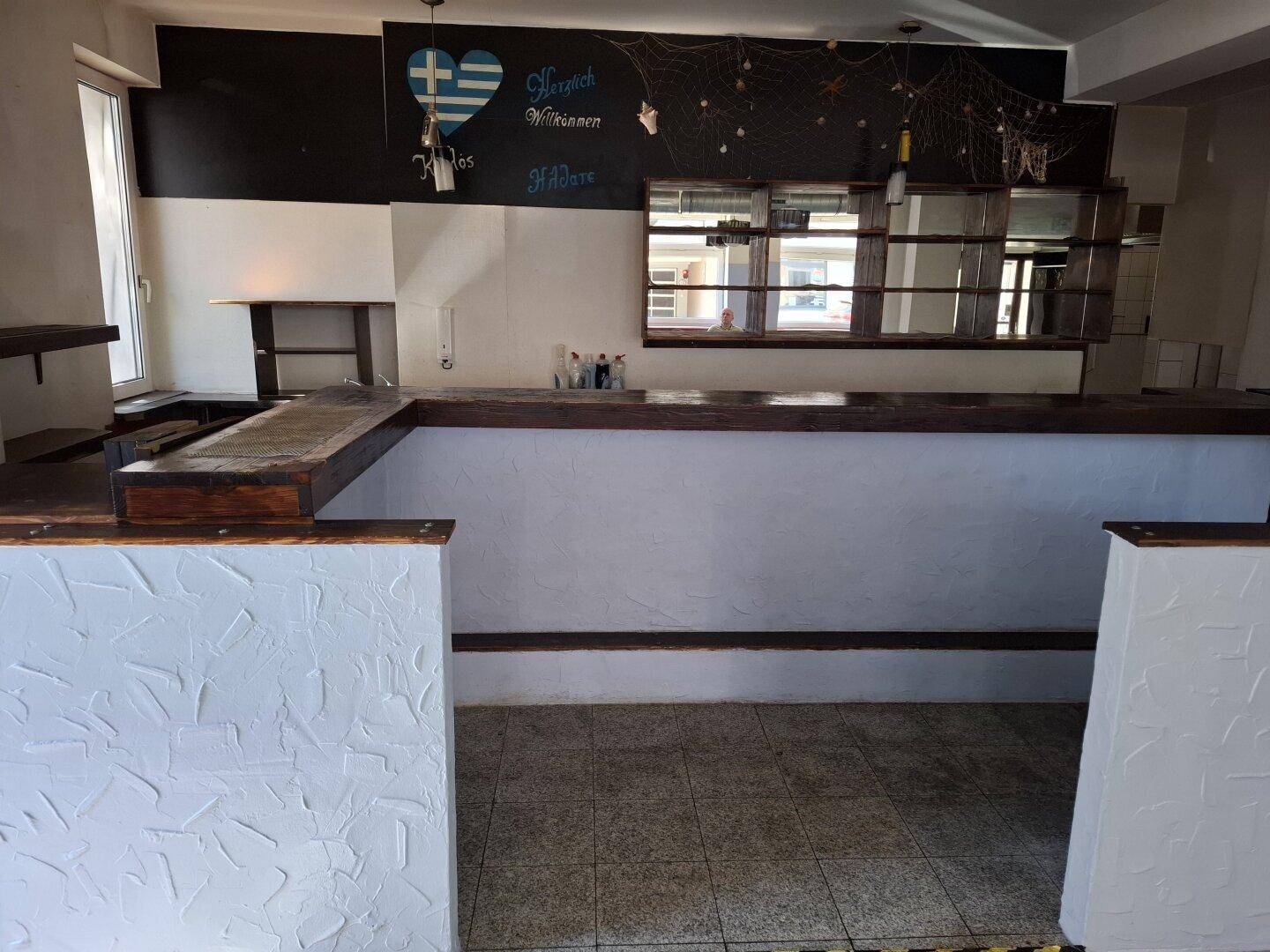Frontansicht des Bar-Bereichs mit strukturierter Thekenverkleidung und dekorativer Wandtafel.