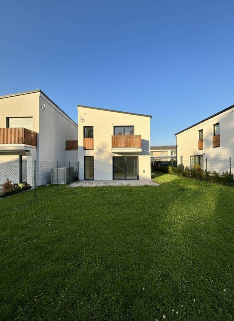Rückseite der Reihenhäuser mit privaten Gärten und kleinen Terrassenbereichen.