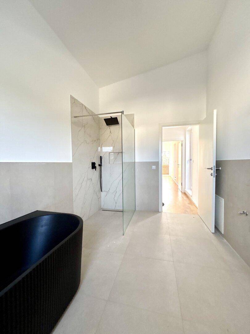 Modernes Badezimmer mit freistehender Badewanne, begehbarer Dusche und Fliesenboden.