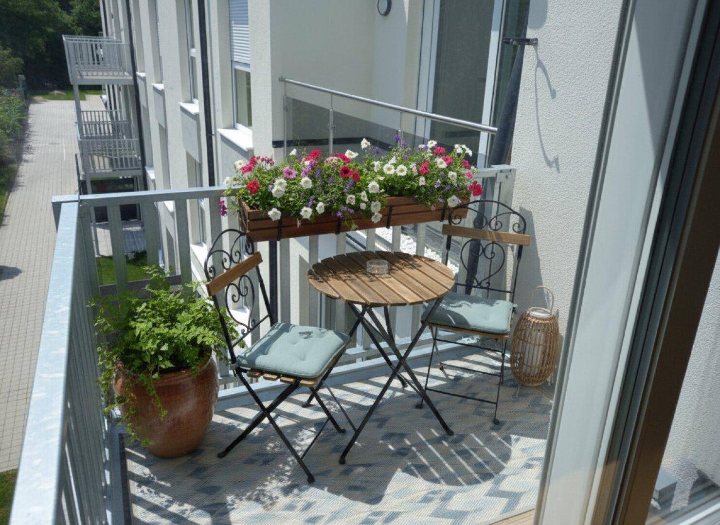 Gemütlicher Balkon mit Sitzgelegenheiten, Blumenkästen und Blick auf die Umgebung.