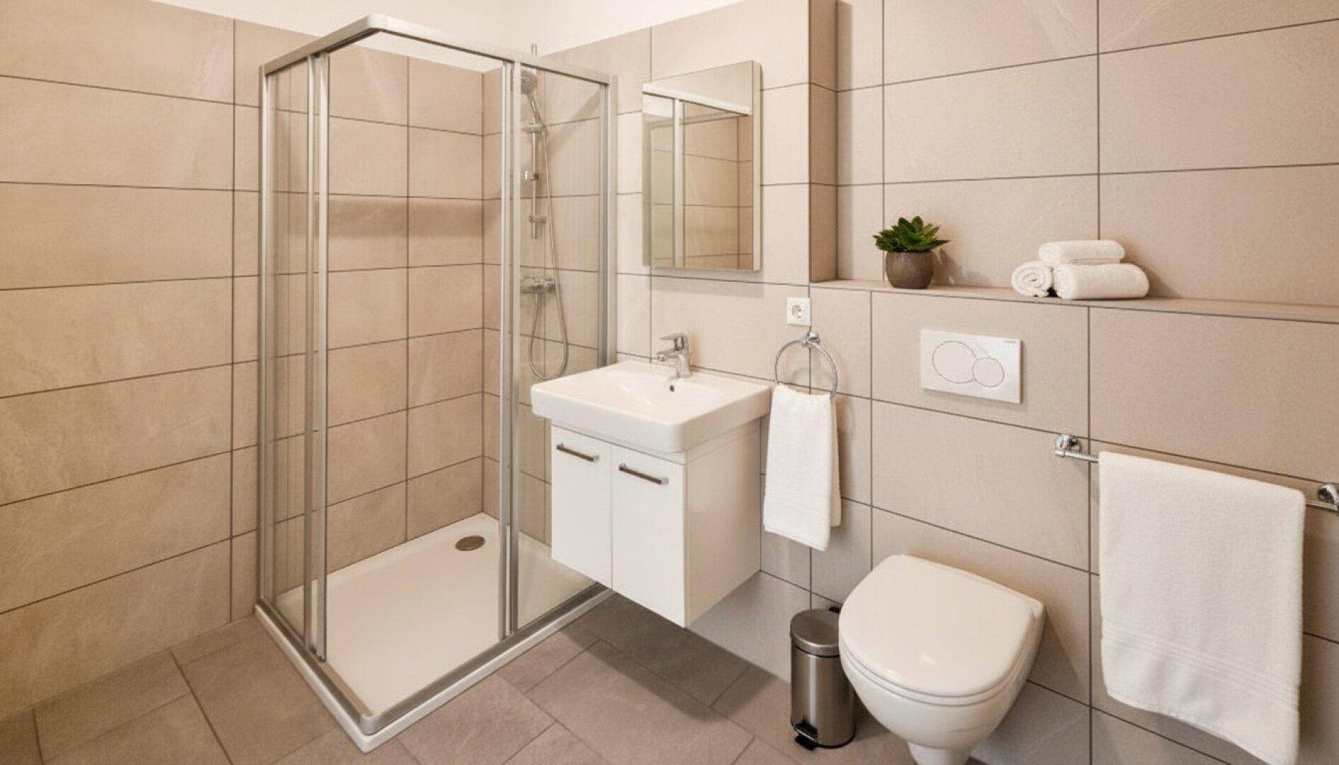 Modernes Badezimmer mit beigefarbenen Fliesen, Duschkabine und wandhängendem WC.