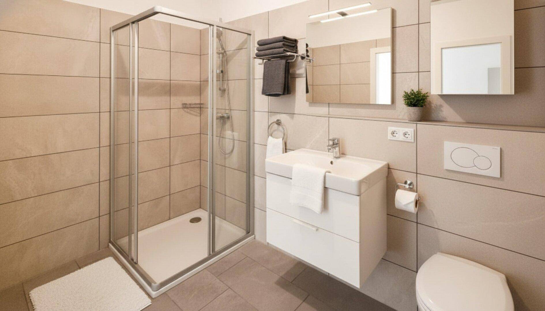Modernes Badezimmer mit Duschkabine, Waschbecken und WC, ausgestattet mit beigefarbenen Fliesen.