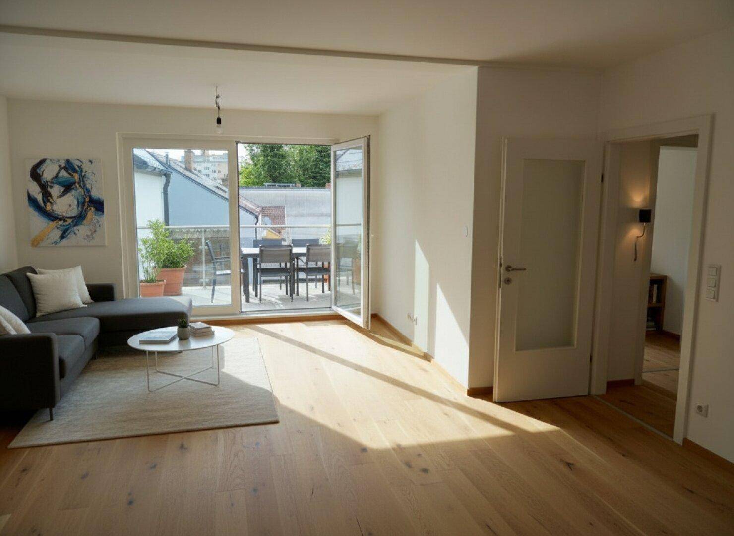 Lichtdurchflutetes Wohnzimmer mit Holzboden, moderner Einrichtung und großem Terrassenzugang.