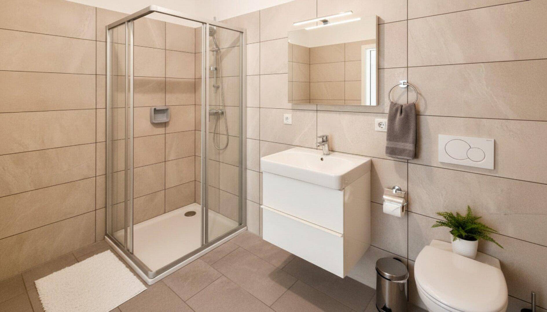 Modernes Badezimmer mit beigefarbenen Fliesen, Duschkabine und wandhängendem WC.