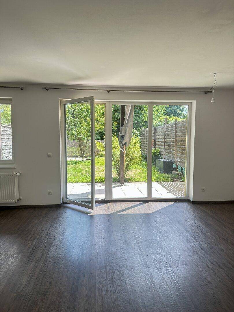 Lichtdurchfluteter Wohnraum mit Laminatboden und direktem Zugang zum grünen Garten.