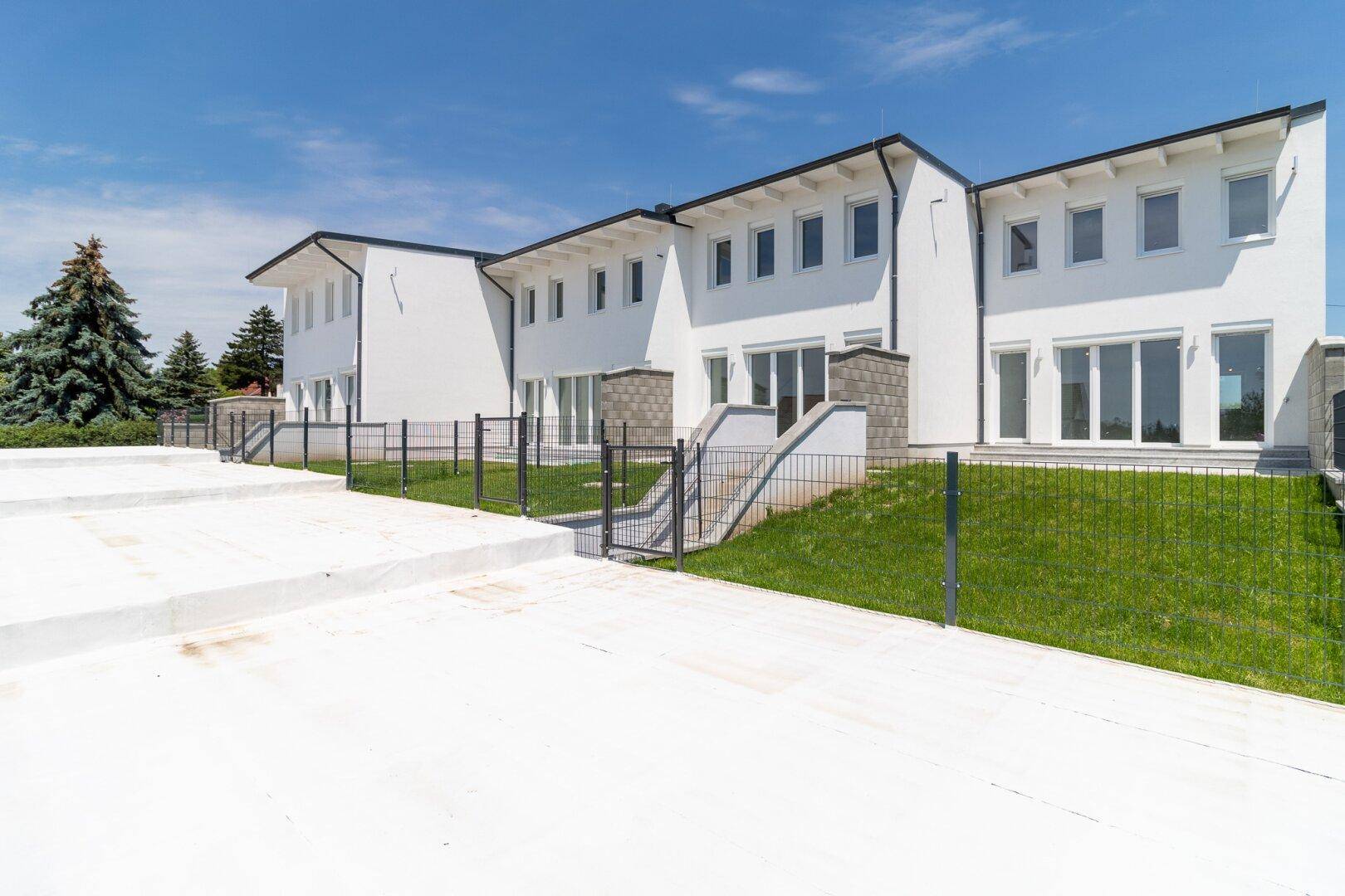 Rückseite der Reihenhäuser mit privaten Gärten und Terrassenbereichen.