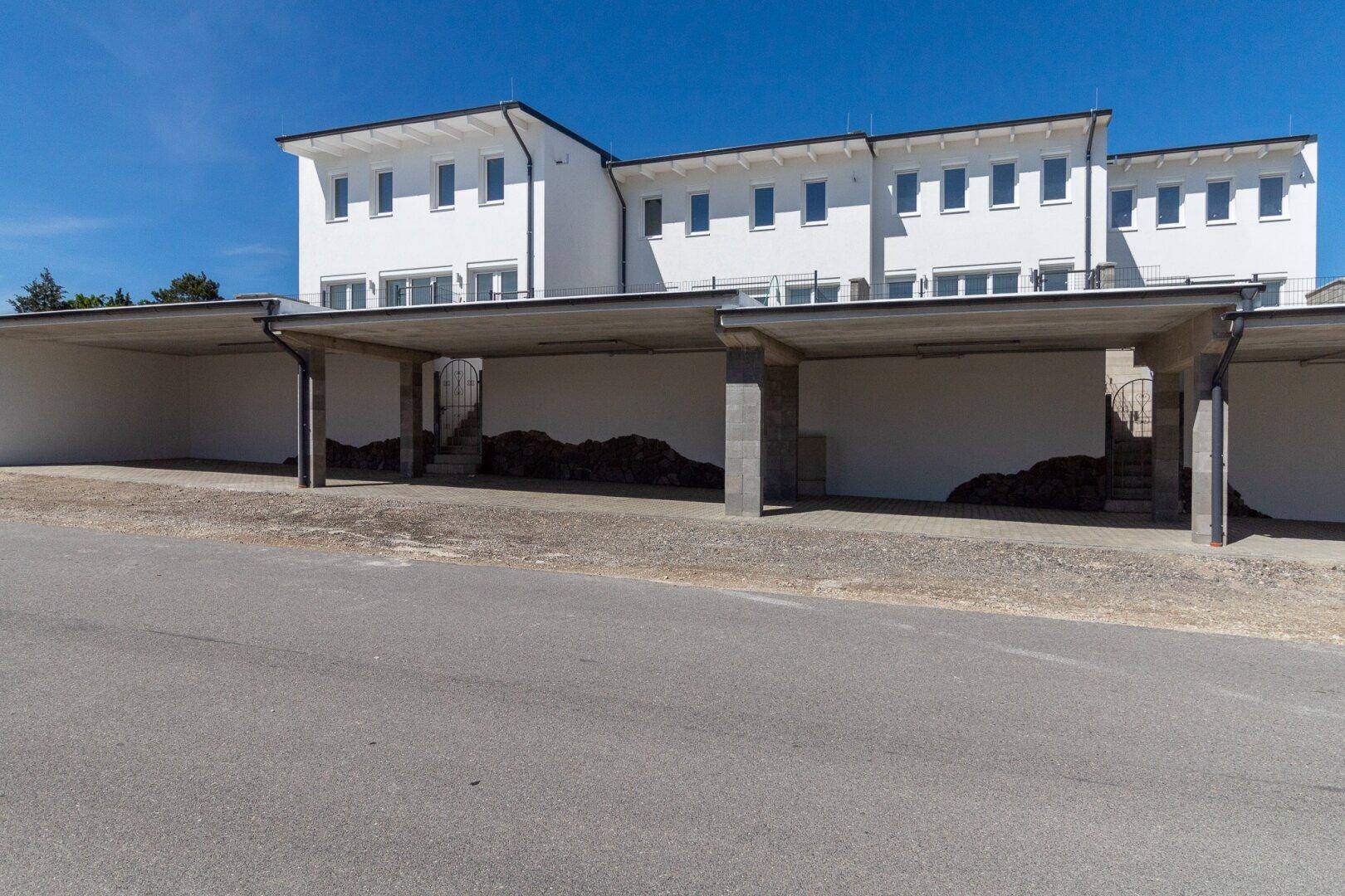 Reihenhäuser mit überdachten Carports und Zufahrt.
