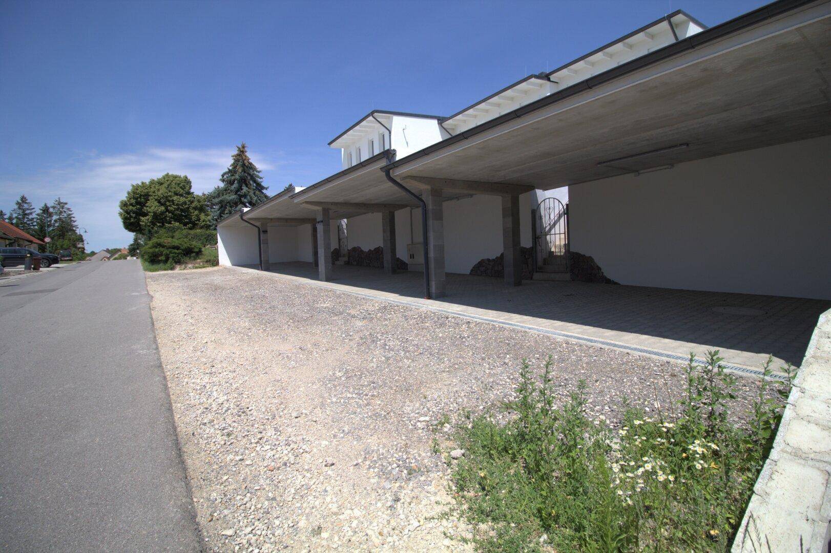 Zufahrtsstraße zu den Reihenhäusern mit Carports und Grünstreifen.
