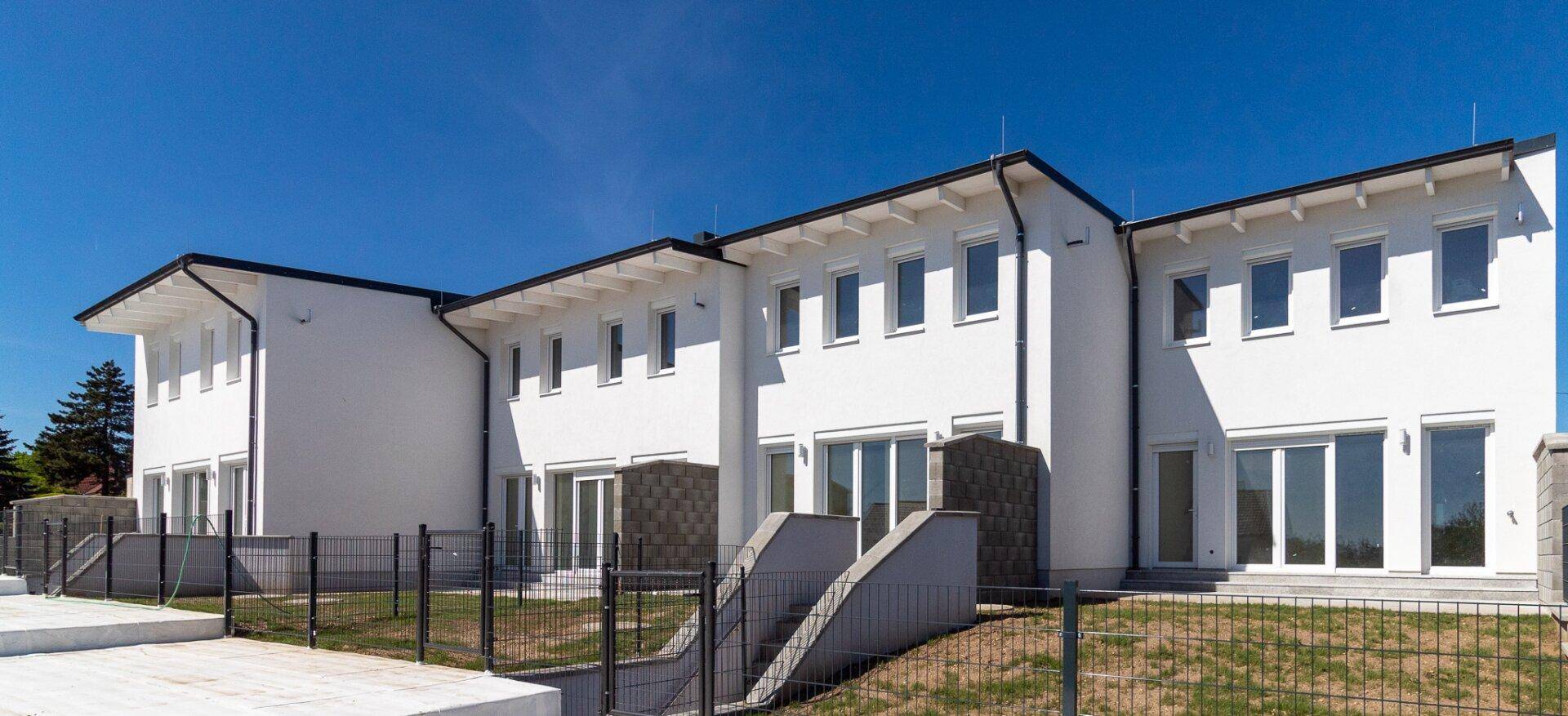 Moderne Reihenhäuser von der Gartenseite mit großen Fensterfronten.