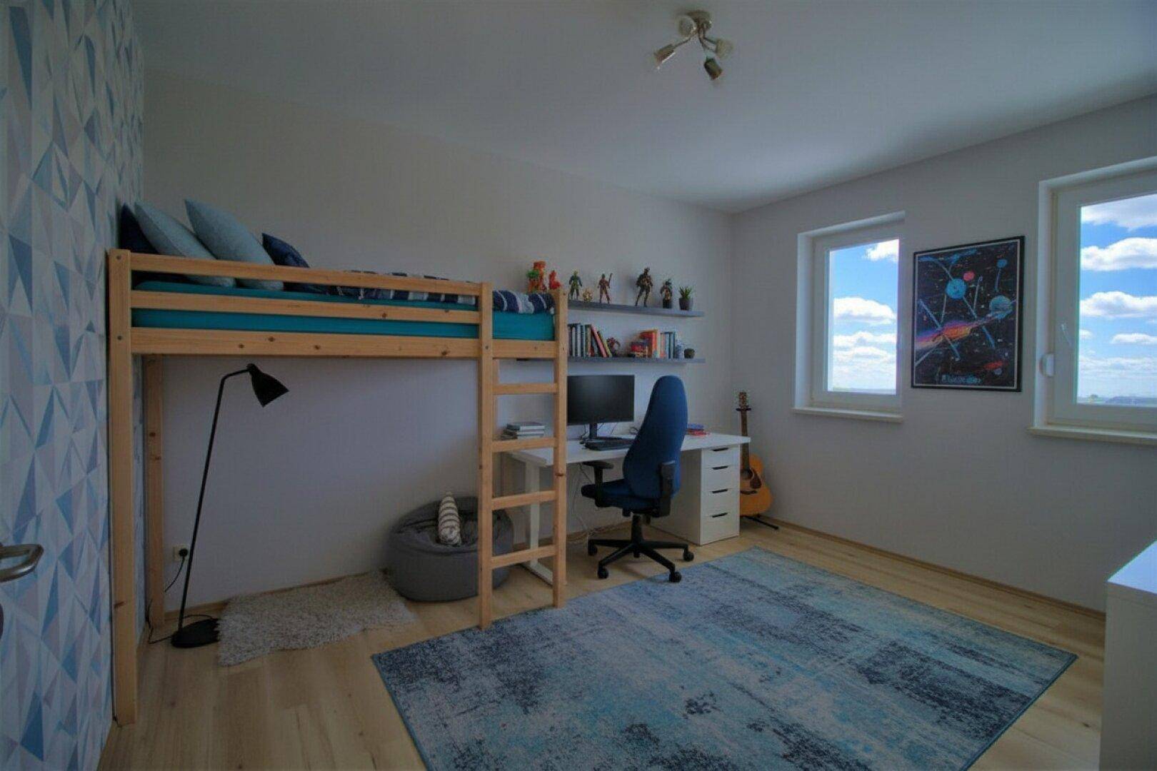 Kinderzimmer mit Hochbett, Schreibtisch und farbenfroher Wandgestaltung.