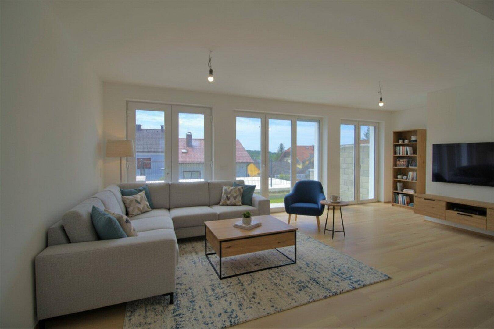Helles Wohnzimmer mit großen Fenstern, Parkettboden und moderner Einrichtung.