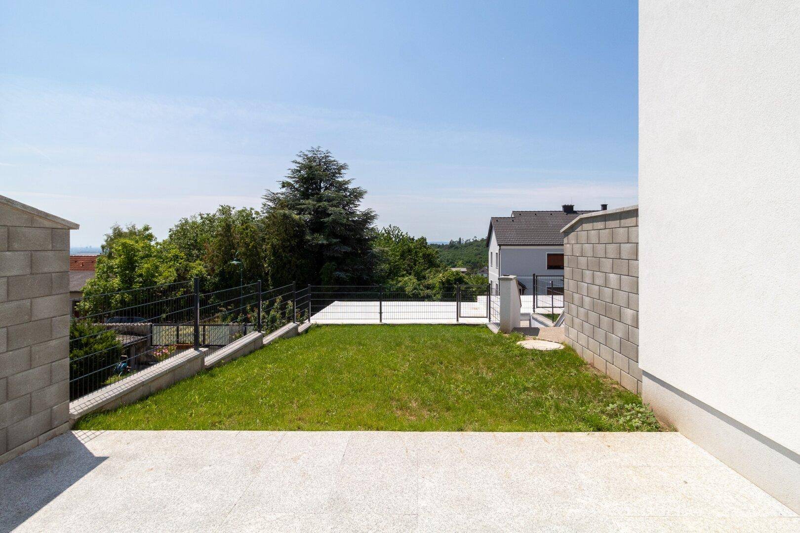 Kleiner Gartenbereich mit Rasenfläche und gepflastertem Zugang hinter dem Haus.