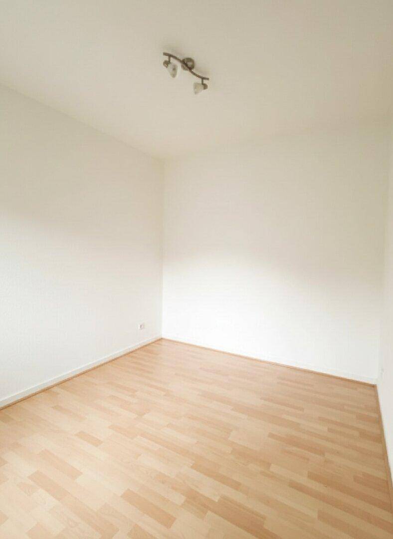 Leerer Raum mit hellem Parkettboden und weiß gestrichenen Wänden, bereit zur Einrichtung.