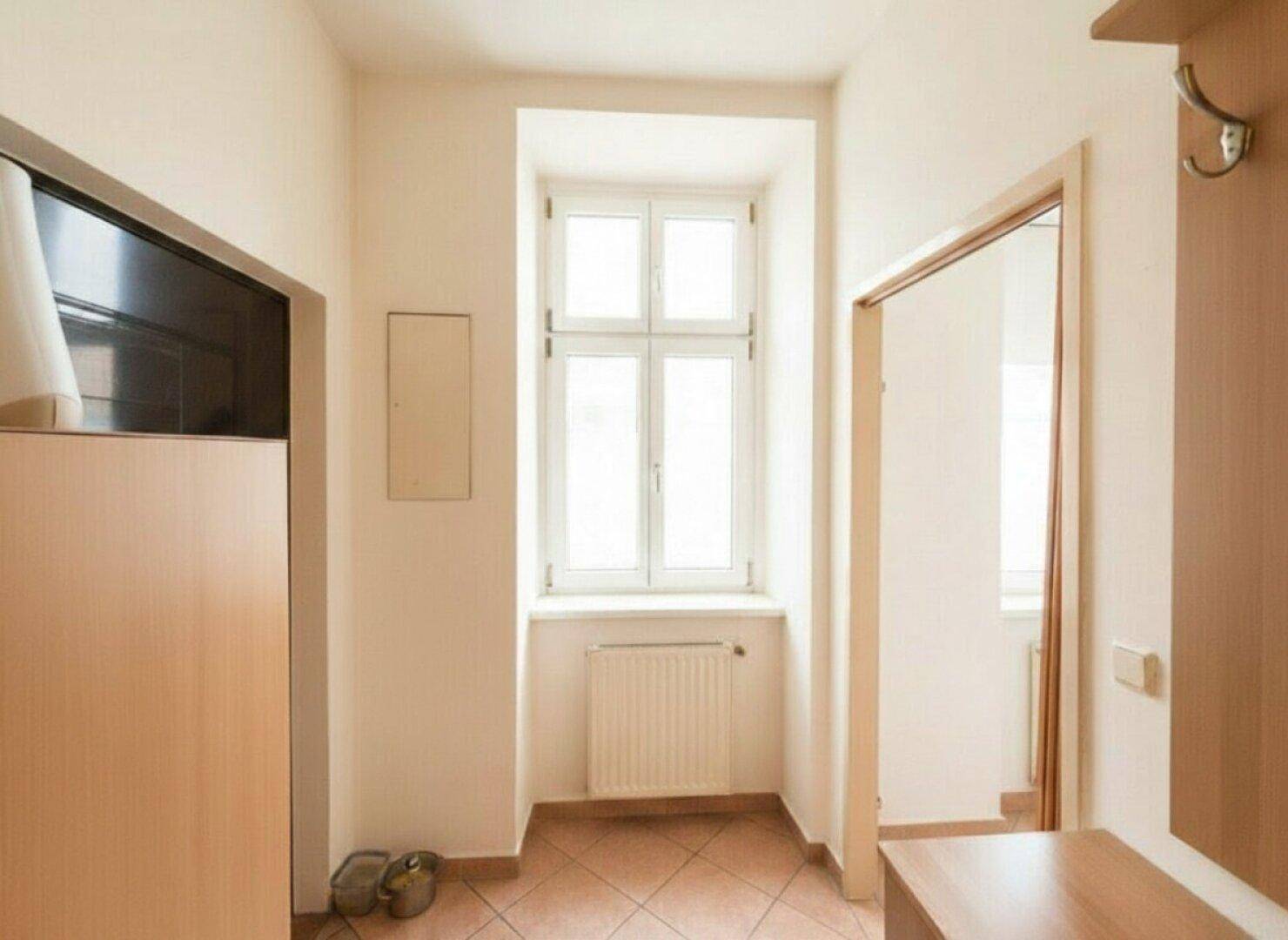 Eingangsbereich mit Fliesenboden, Fenster und einem praktischen Garderobenbereich.
