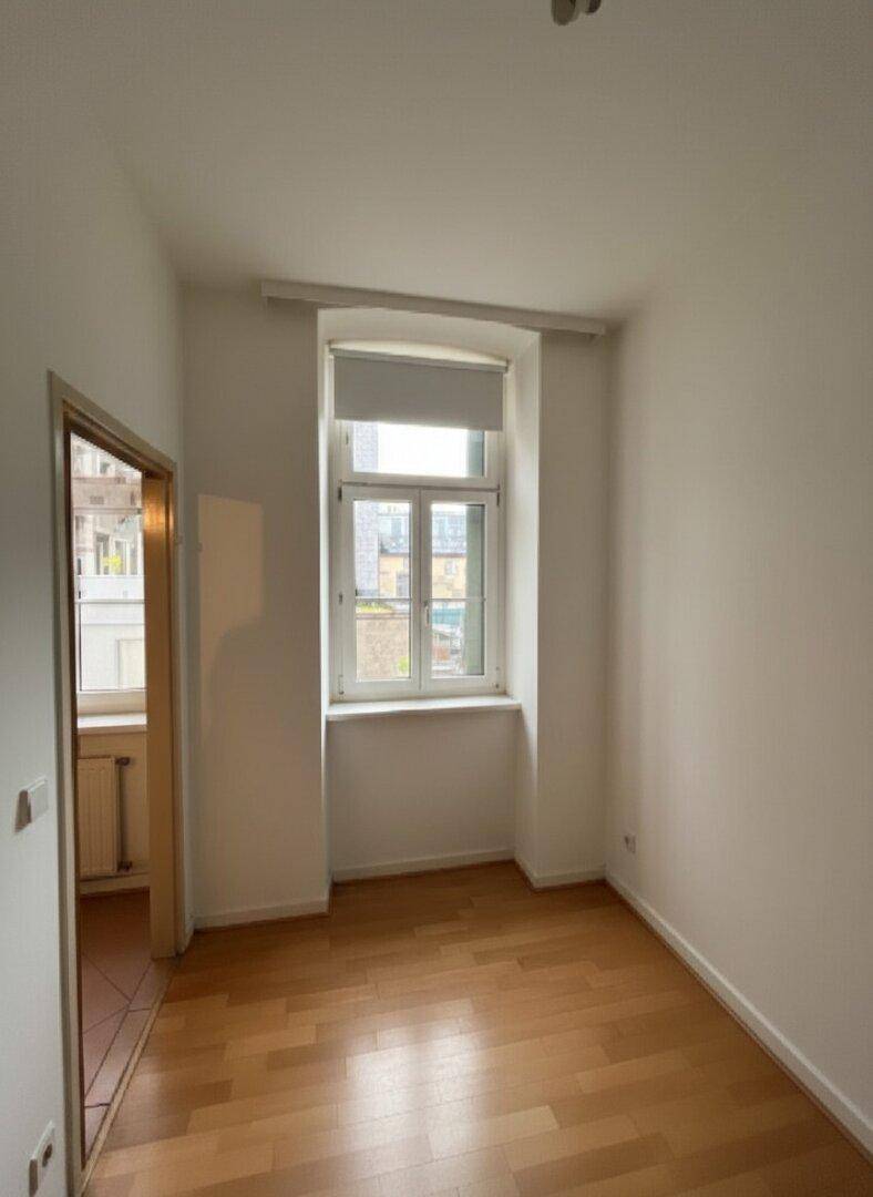 Kleineres Zimmer mit einem Fenster und hellem Parkettboden, ideal als Schlaf- oder Arbeitszimmer.