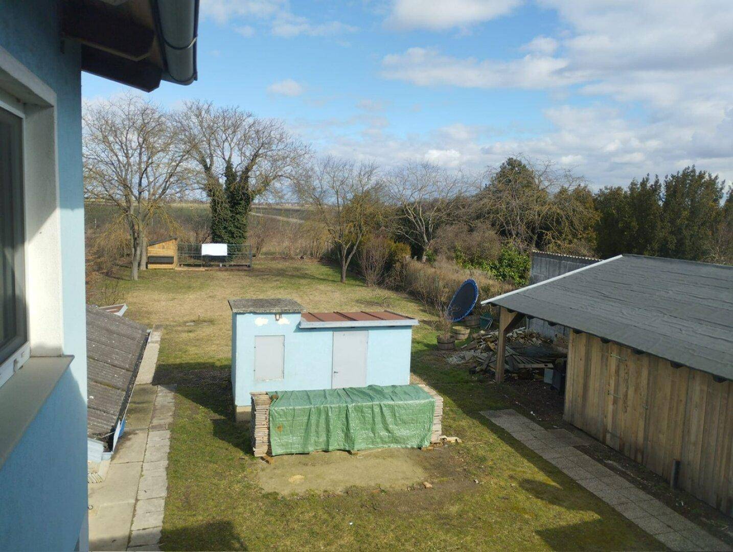 Blick auf den weitläufigen Gartenbereich mit Nebengebäuden und ländlicher Umgebung.