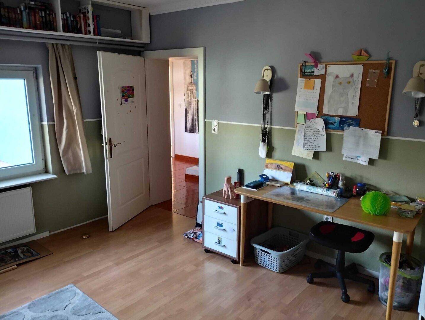 Kinderzimmer mit Schreibtisch, Holzfußboden und zweifarbiger Wandgestaltung.