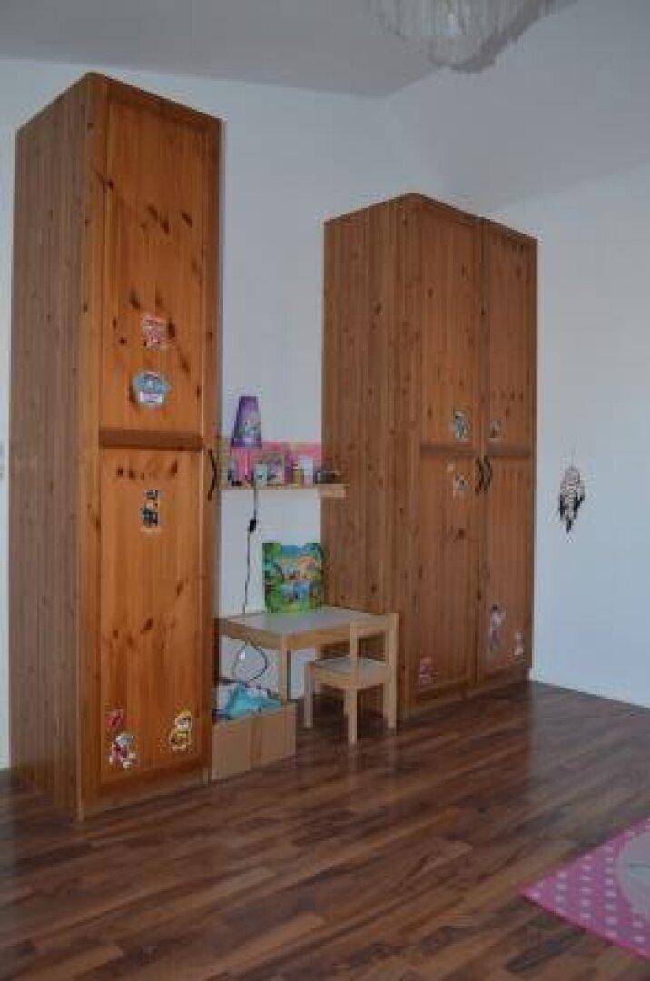 Kinderzimmer mit zwei hohen Holzschränken und Laminatboden, praktisch und geräumig.