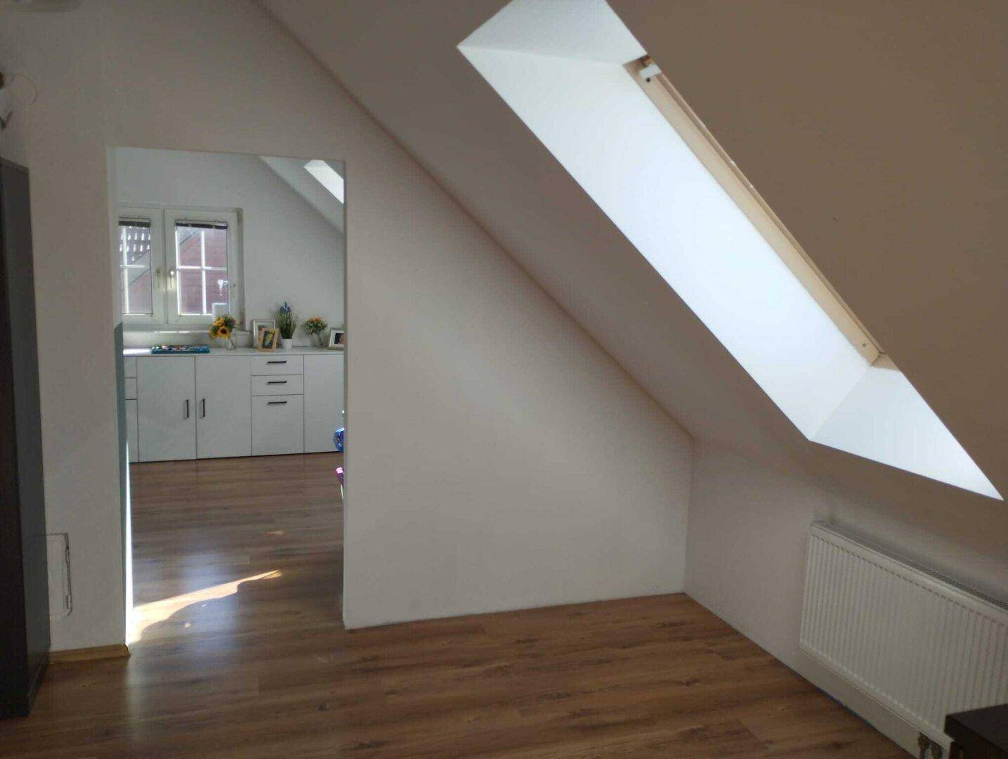 Dachgeschossraum mit Laminatboden und Dachfenster, bietet viel natürliches Licht.