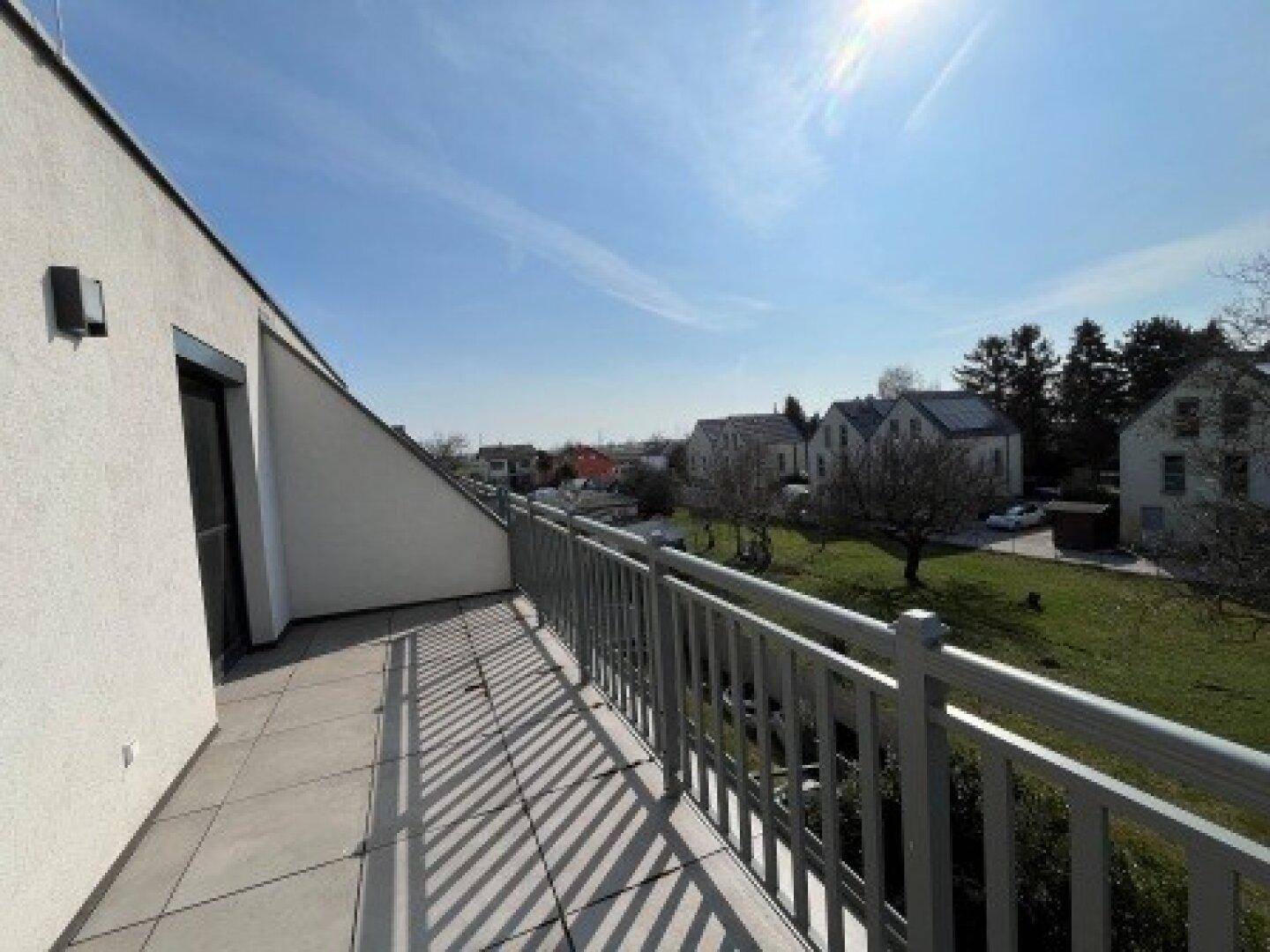 Sonniger Balkon mit Fliesenboden und Blick auf die grüne Umgebung, ideal zum Entspannen im Freien.