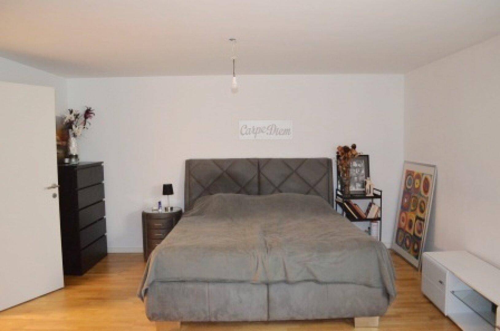 Geräumiges Hauptschlafzimmer mit großem Bett, dunklen Möbeln und Holzboden, bietet viel Komfort.