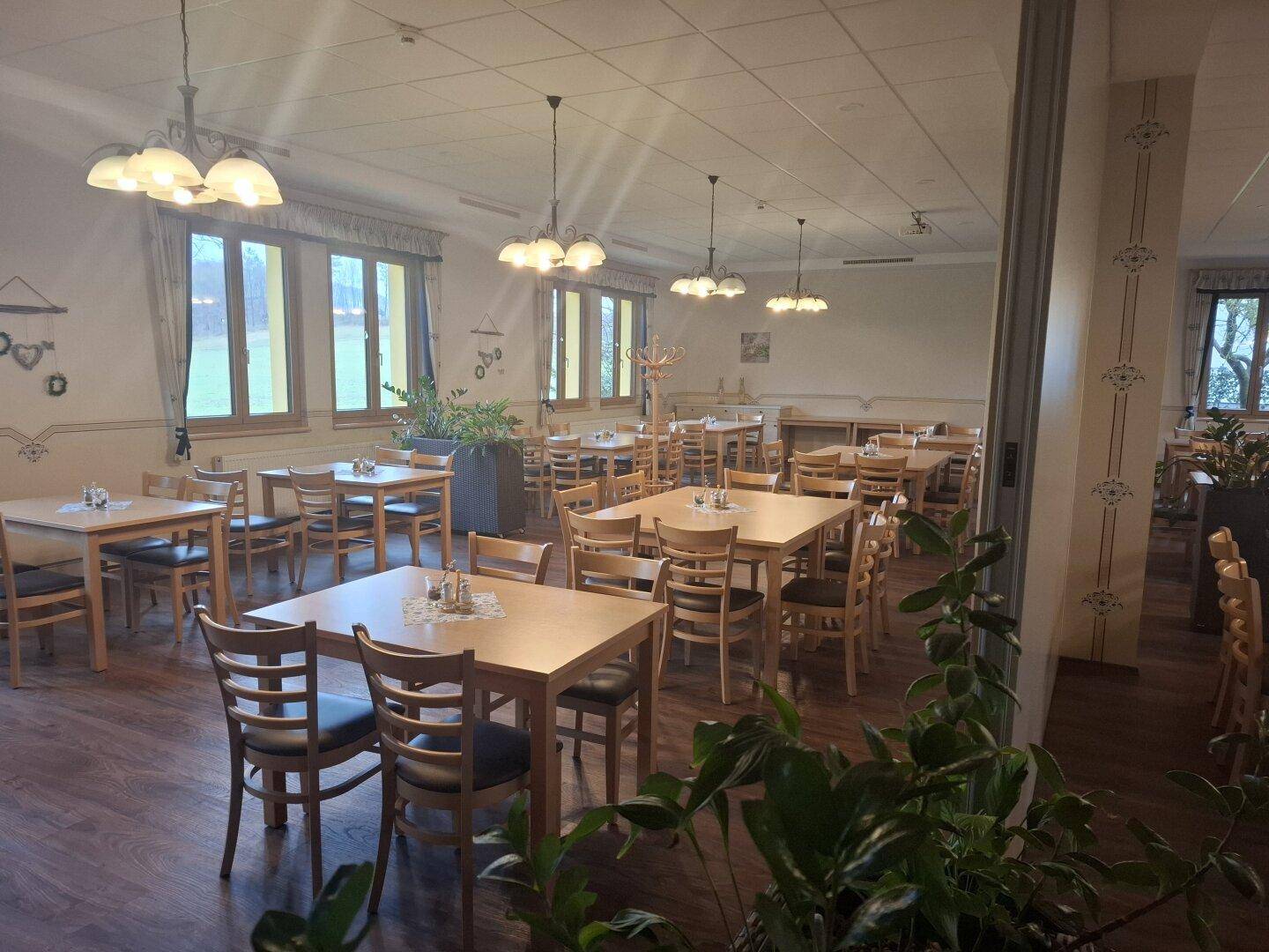 Heller, geräumiger Speisesaal mit vielen Holztischen und Stühlen, ideal für größere Gruppen.