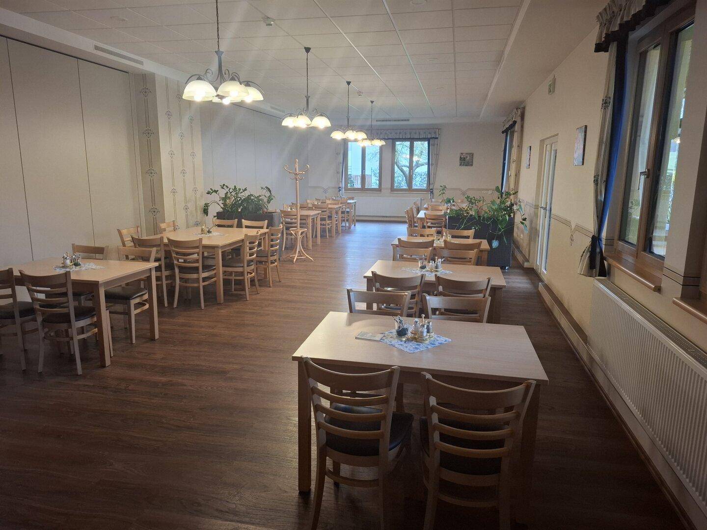Langer Speisesaal mit Holzboden und großen Fenstern, bietet Platz für zahlreiche Gäste.