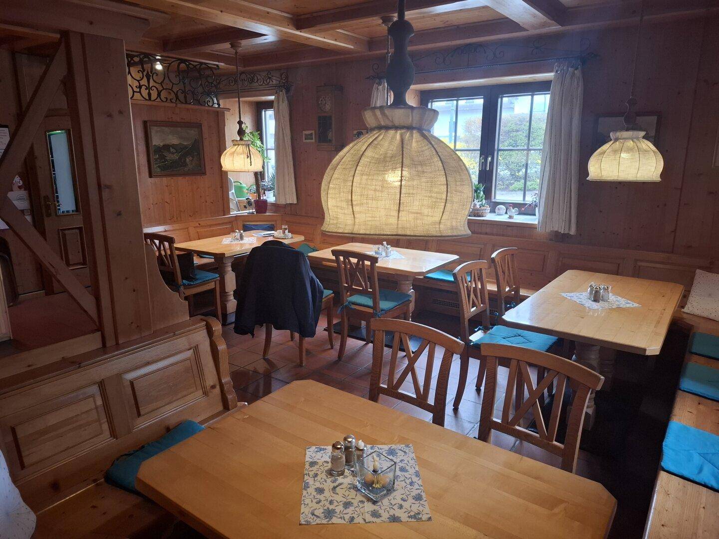 Gemütlicher Speiseraum mit Holzvertäfelung, traditionellen Möbeln und großen Fenstern.