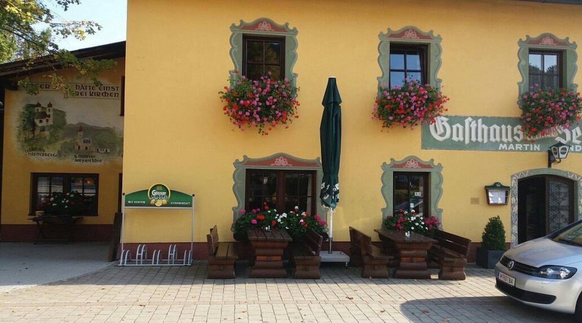 Traditionelle Gasthausfassade mit Blumenkästen an den Fenstern und einem Eingangsbereich.