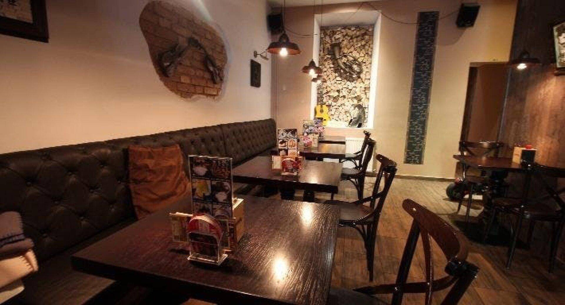 Gemütlicher Restaurantbereich mit dunklen Holztischen, gepolsterten Sitzbänken und gedämpfter Beleuchtung.