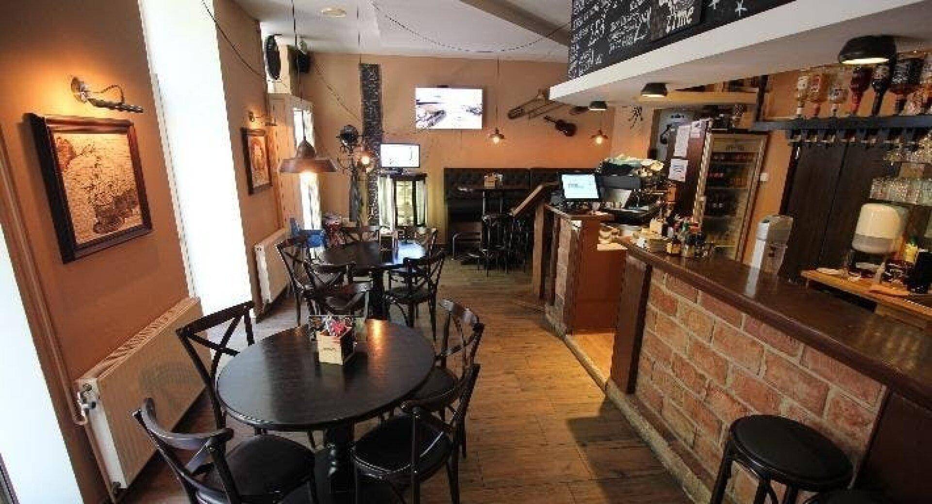 Rustikales Restaurantinterieur mit einer Bar, Holztischen und Stühlen sowie Ziegelakzenten an der Theke.
