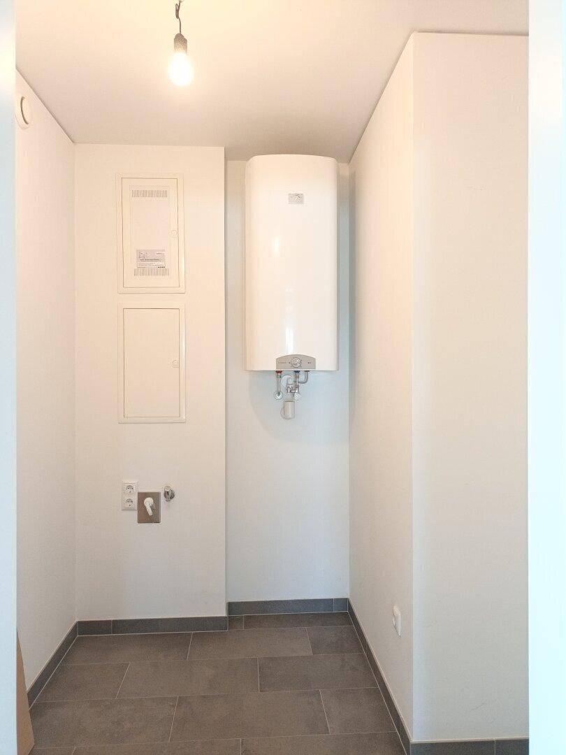 Praktischer Hauswirtschaftsraum mit Warmwasserboiler und Anschlüssen, ideal für Technik und Lagerung.