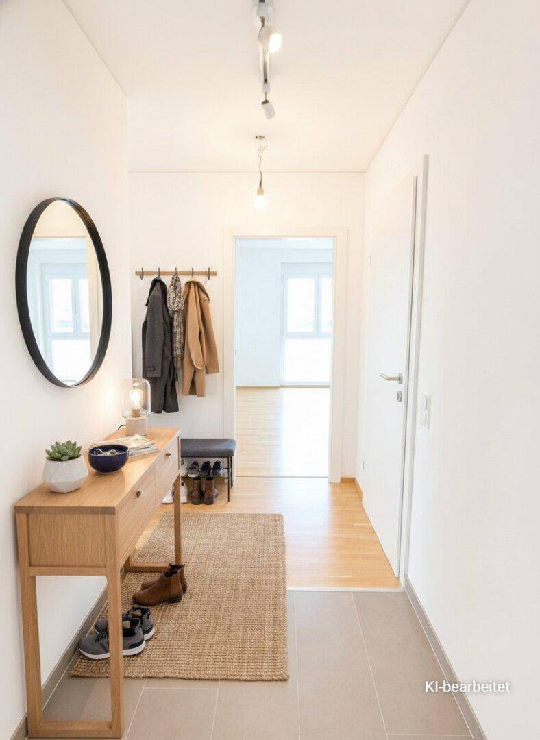 Heller Flur mit Holzboden, Garderobe und Spiegel, der zu weiteren Räumen führt.