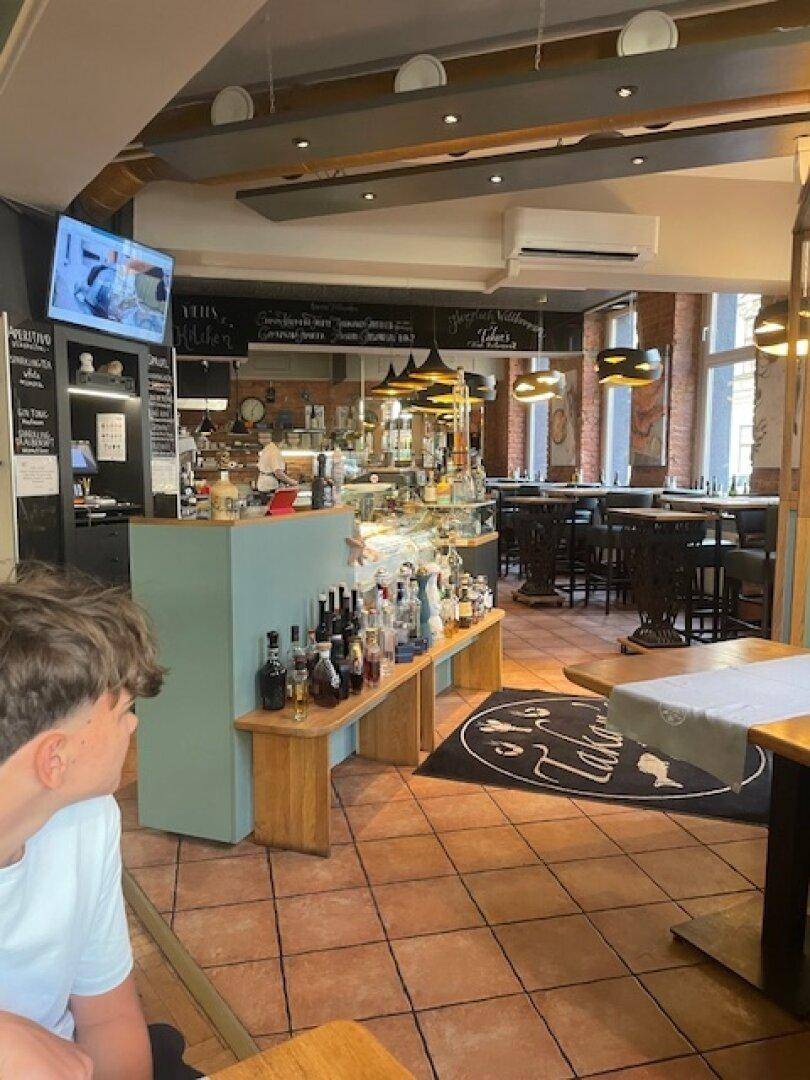 Ein lebhaftes Café mit einer Theke, Fliesenboden, sichtbaren Ziegelwänden und modernen Leuchten.