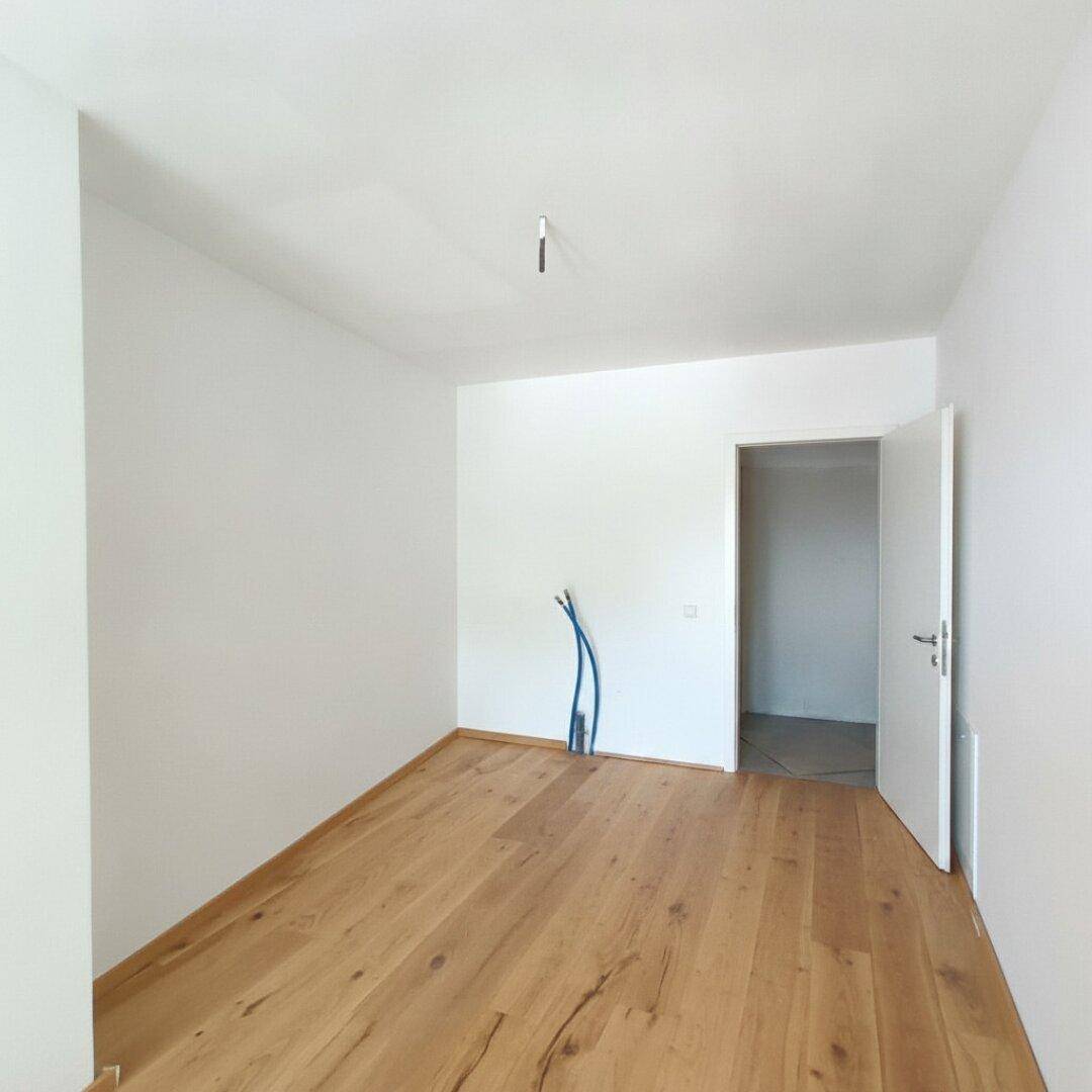 Leerer Raum mit Holzboden und offener Tür, vorbereitet für weitere Installationen.