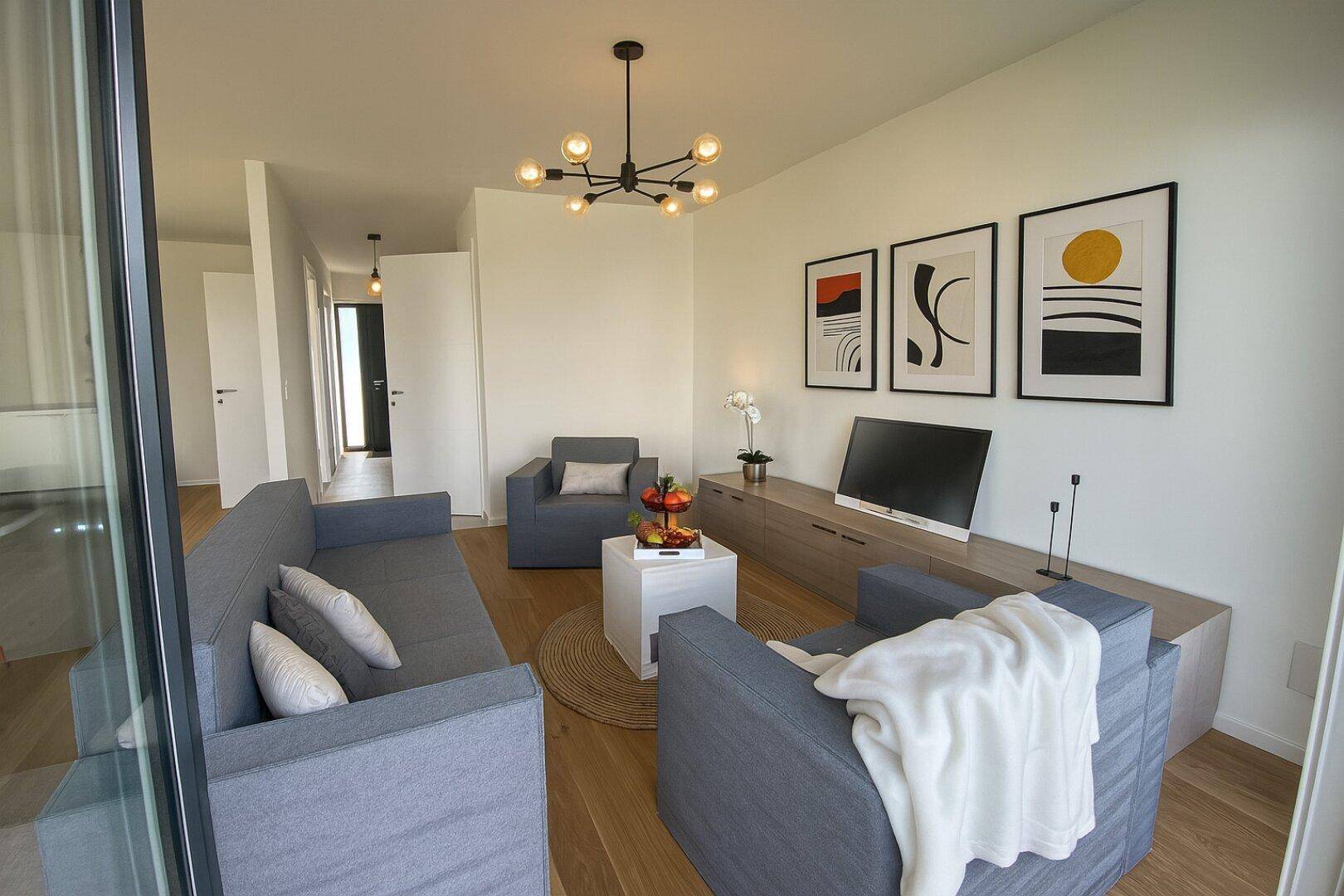 Gemütliches Wohnzimmer mit modernem Sofa, stilvollen Bildern und hellem Holzboden.