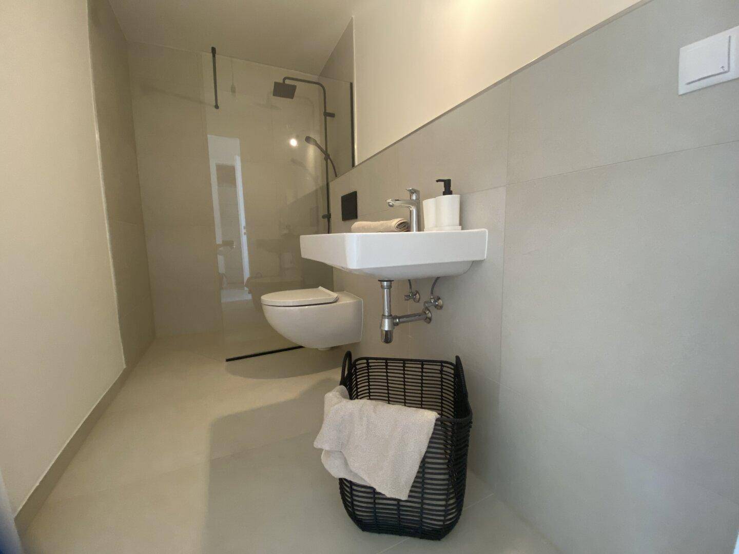 Modernes Badezimmer mit begehbarer Dusche, Wand-WC und minimalistischem Waschbecken.