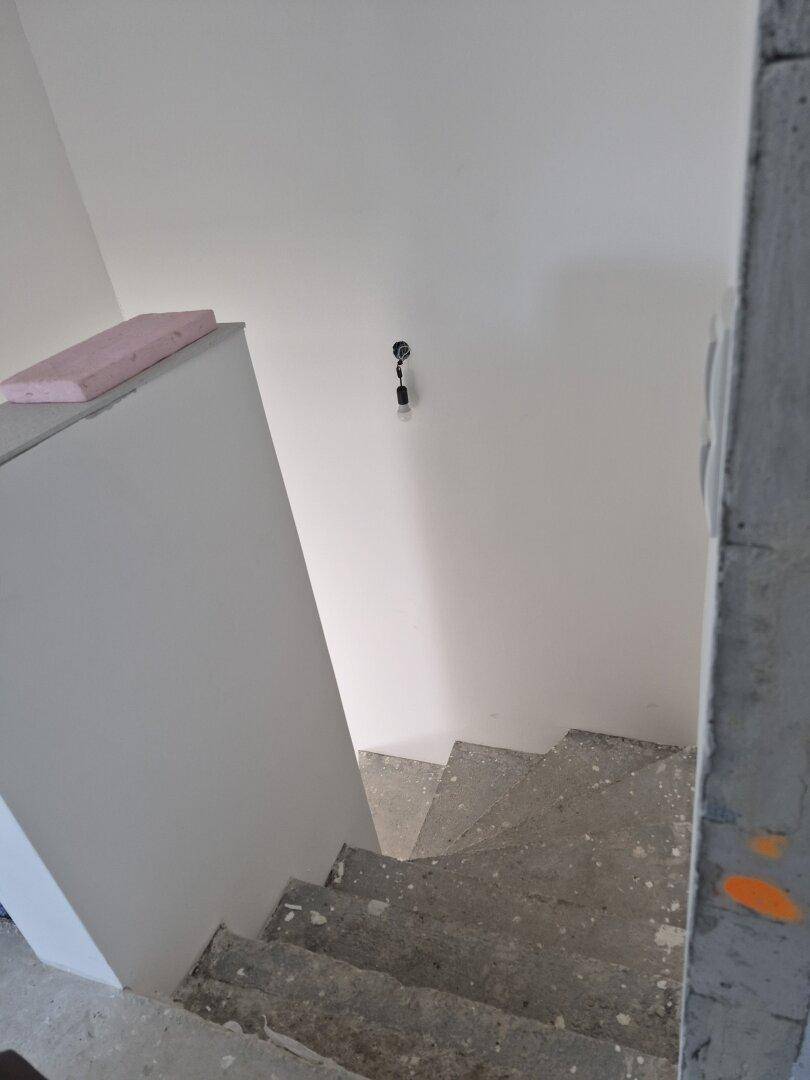 Unfertige Betontreppe, die in ein oberes Stockwerk führt, mit weiß gestrichenen Wänden.