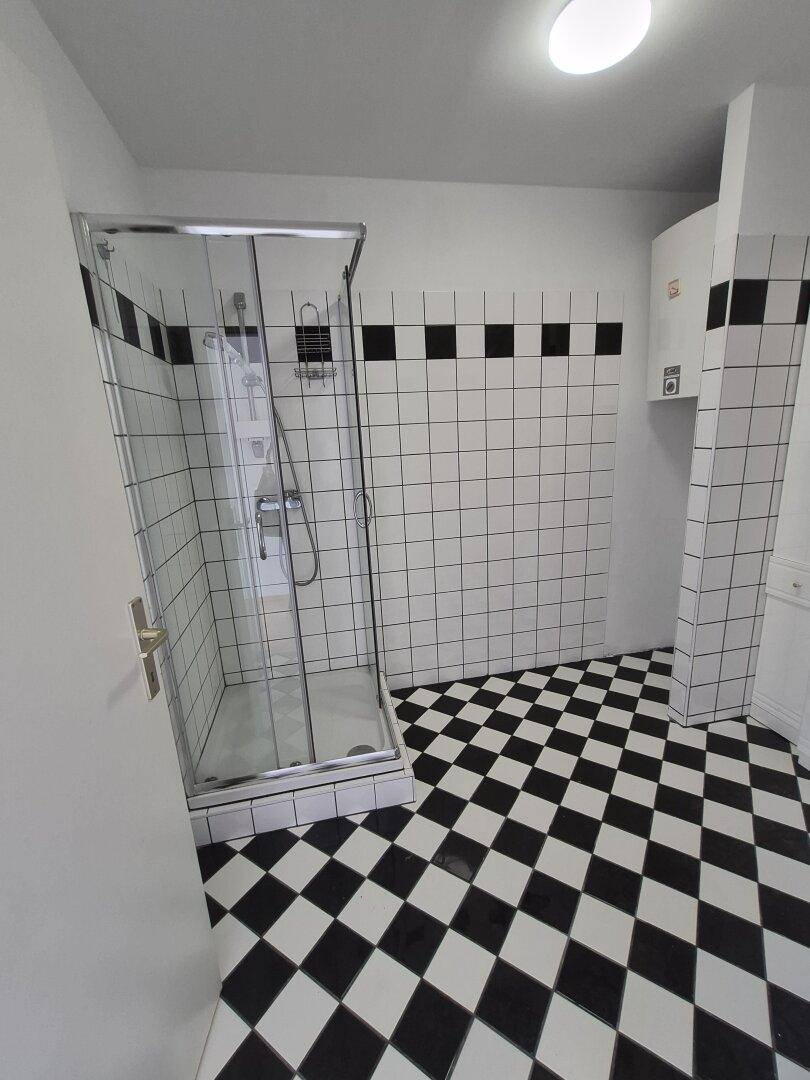 Badezimmer mit markanten schwarz-weißen Fliesen und einer modernen Duschkabine.