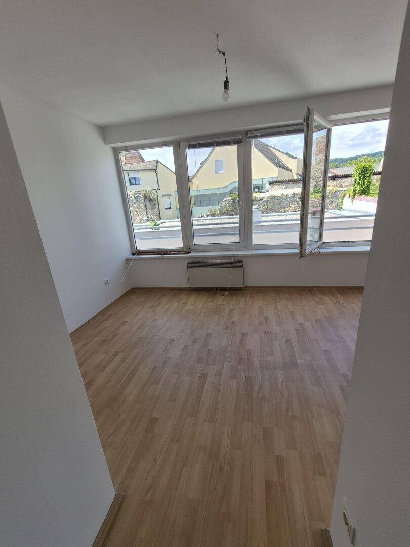 Heller Wohnraum mit großen Fenstern und Holzparkett, bietet viel natürliches Licht und Ausblick.