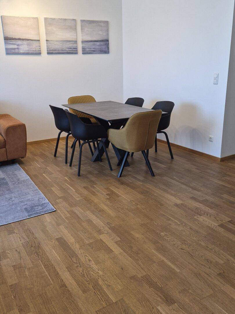 Essbereich mit modernem Tisch und Stühlen auf Holzboden, dekoriert mit Kunstwerken.