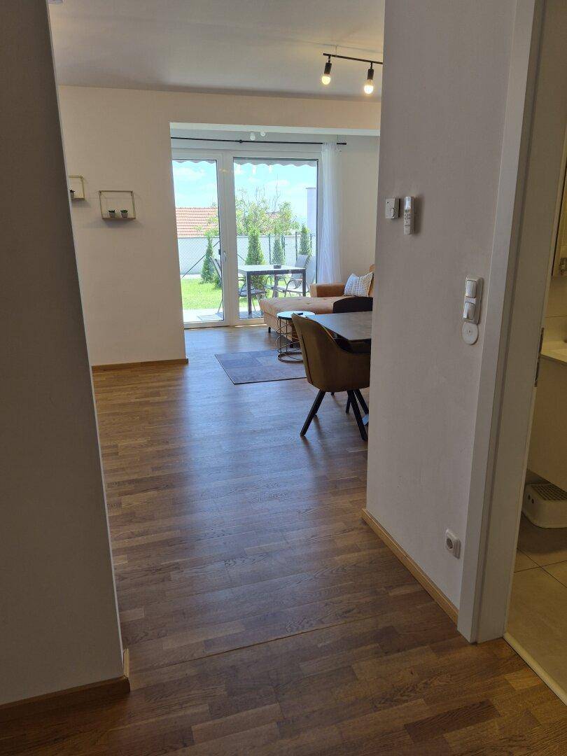 Blick vom Flur in den hellen Wohnbereich mit Holzboden und Gartenzugang.