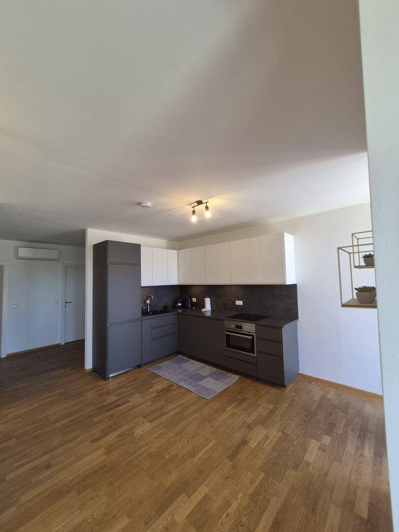 Moderne Einbauküche mit weißen und grauen Schränken und Holzboden.