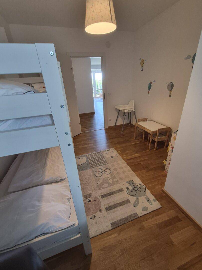 Kinderzimmer mit Etagenbett, Holzboden und spielerischer Wanddekoration.