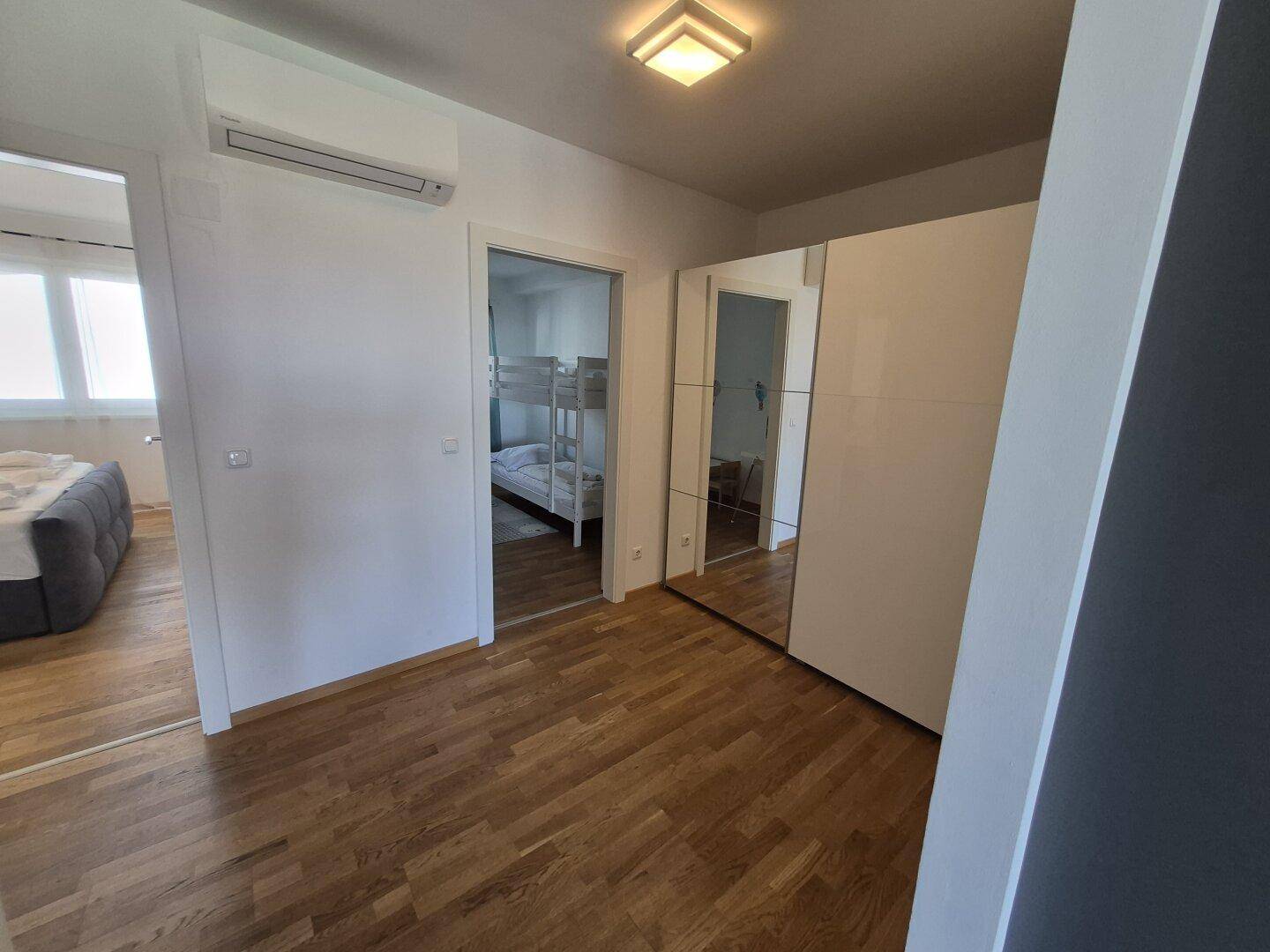 Heller Flur mit Klimaanlage und Spiegelschrank, der zu den Schlafzimmern führt.