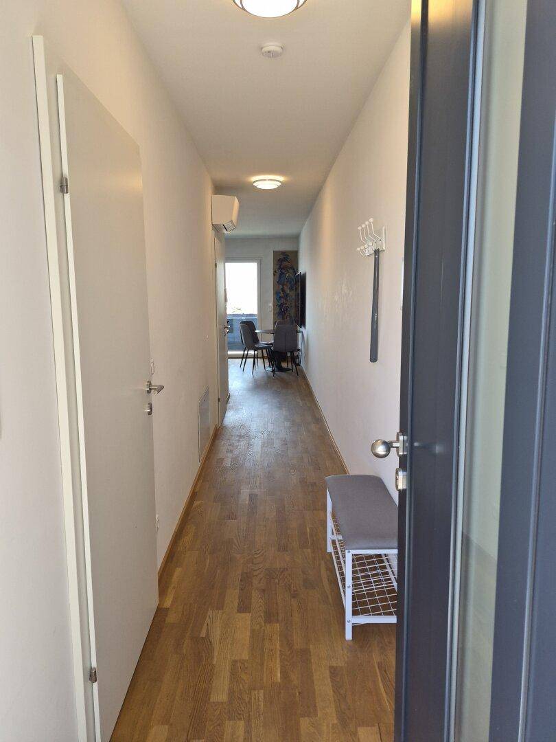 Langer, heller Flur mit Holzfußboden, der zu den Wohnbereichen führt.